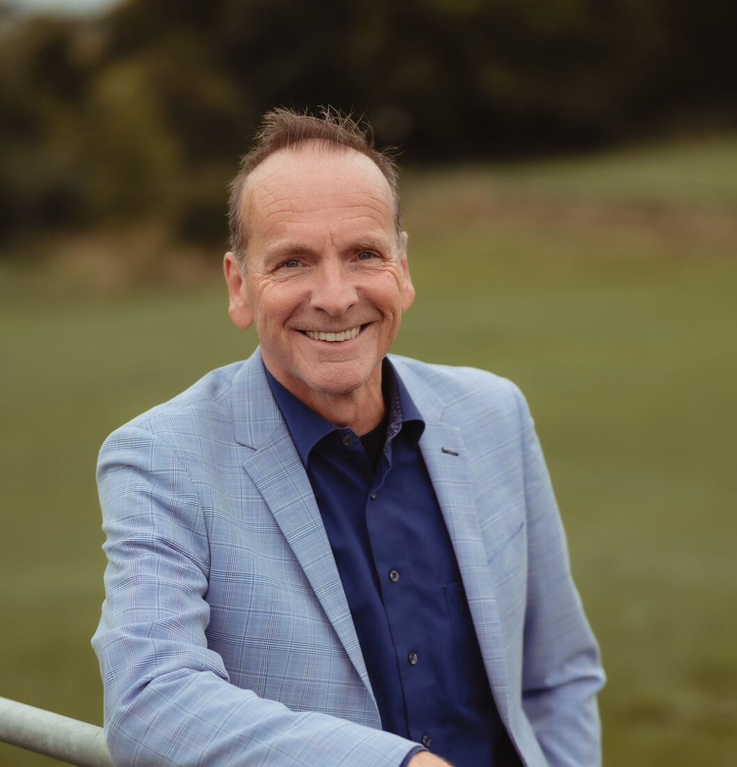 Wim Dupont buiten aan een hek, op de achtergrond een grasland met daarachter met bomen