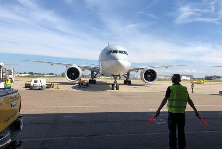 Een marshaller met op de achtergrond een vliegtuig op Maastricht Aachen Airport