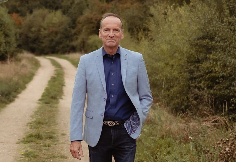 Wim Dupont buiten op een veldweg met begroeiing aan de zij- en achterkant